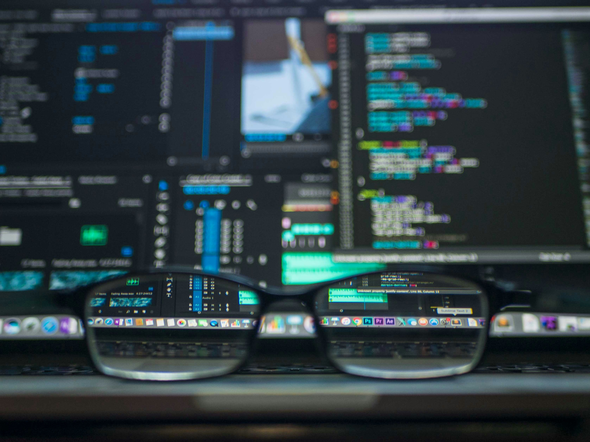 Developer glasses reflecting complex code across multiple screens in a systems operations workspace